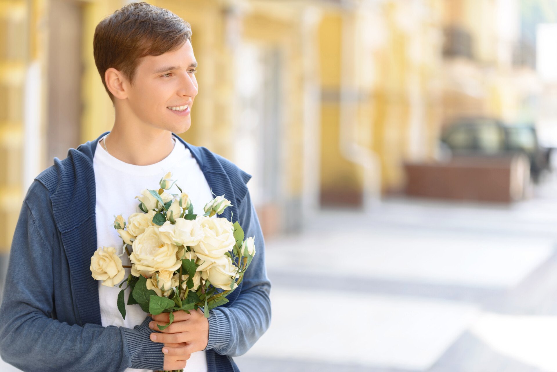 Handsome Guy Holding Flowers Pleasant cheerful handsome young guy looking aside and holding bouquet of flowers while feeling happy
