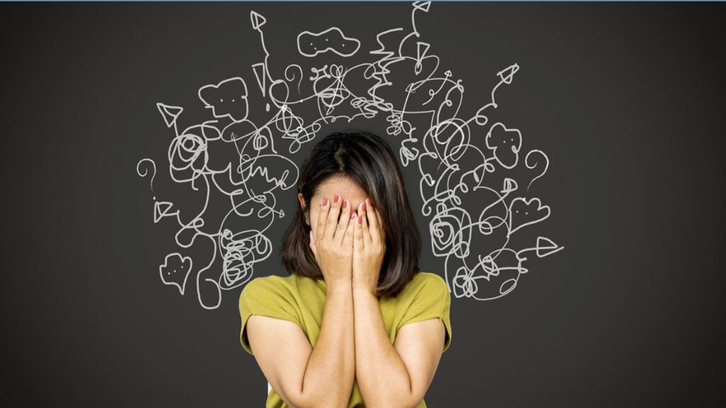 What Is A Panic Attack Hangover? 1 woman with hands covering her face with messy lines coming off her.