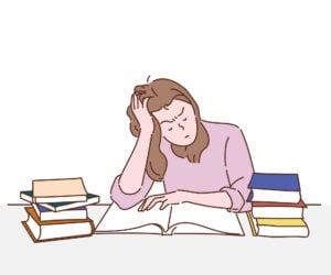A burnt out student attempting to read textbooks at a desk