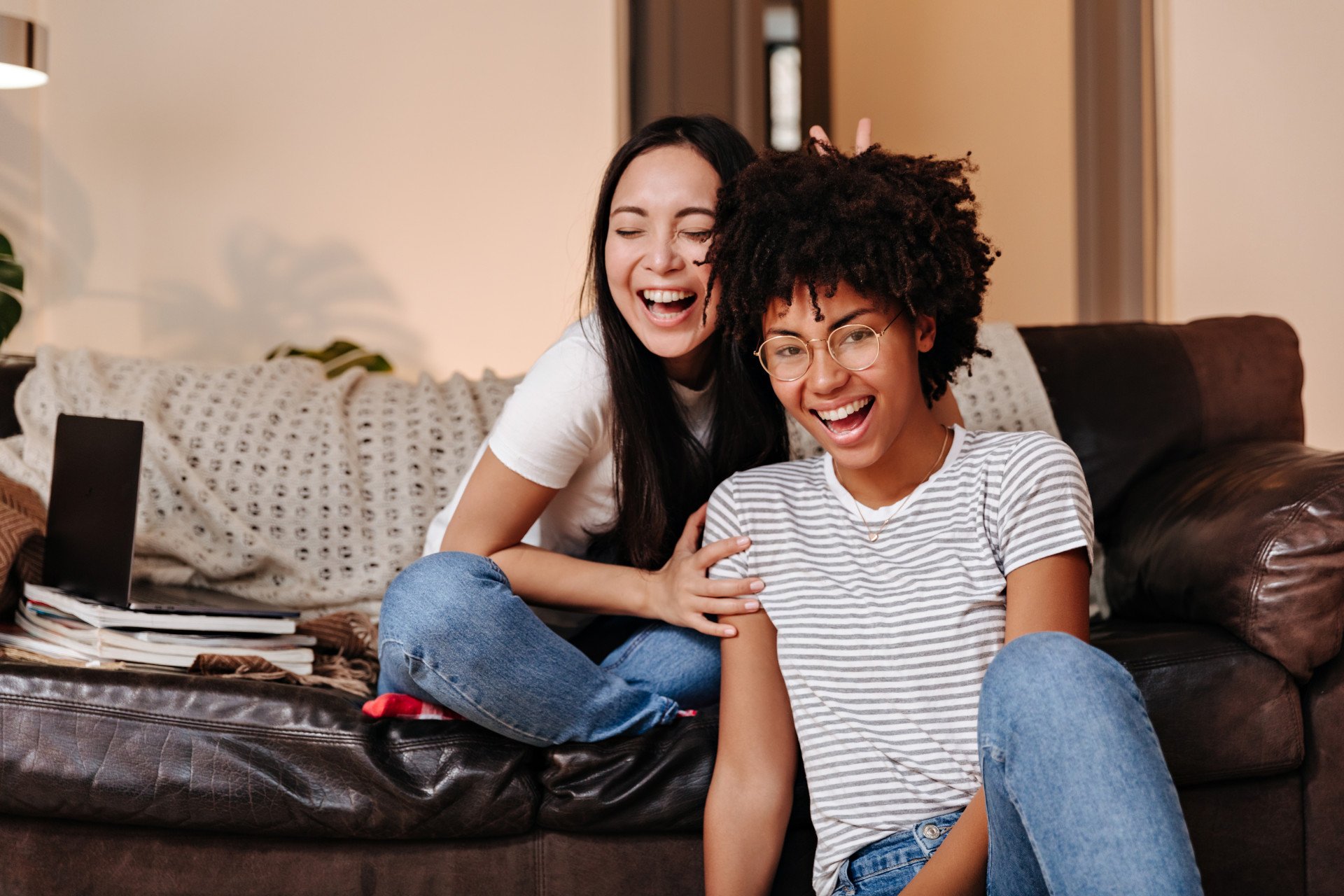 Two friends sat in a lounge together laughing and being playful.