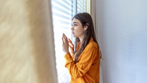 Photo of a woman looking fearful out the window.