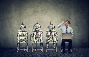 A man sat on a chair next to three robots