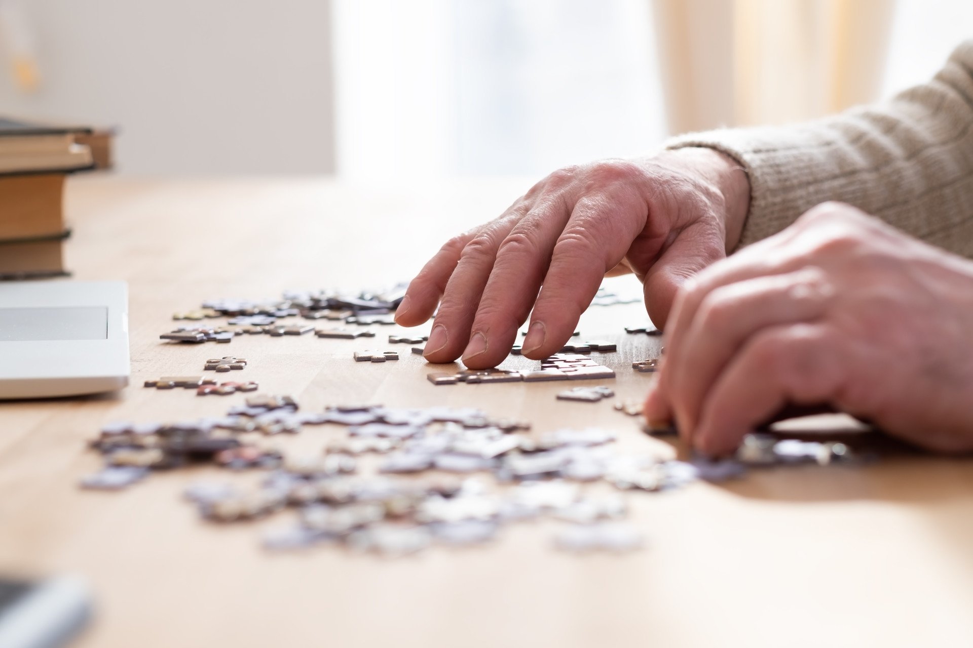 A close up of an older adult's hands putting a jigsaw puzzle together.