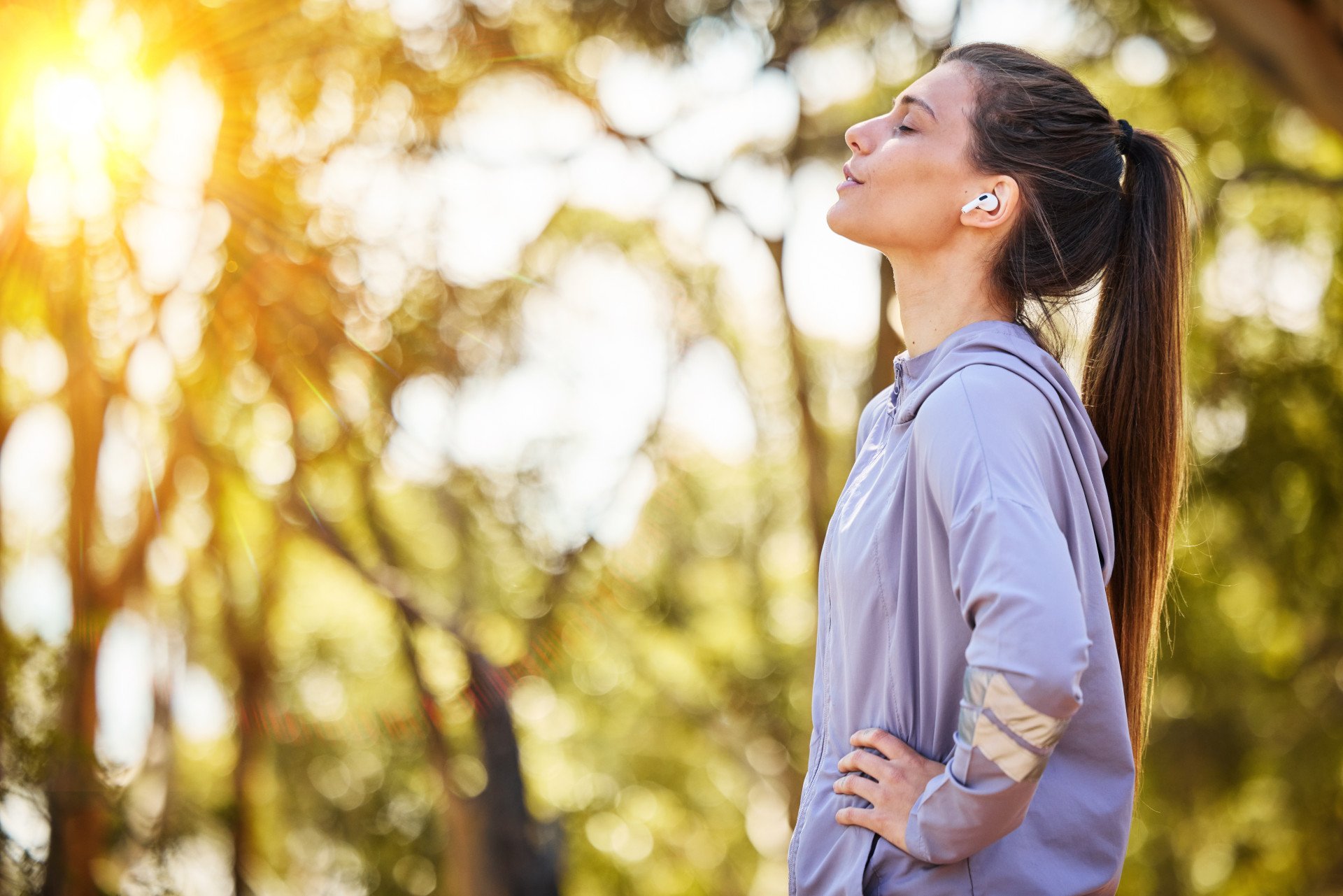 A woman taking a deep breath outdoors after a run.