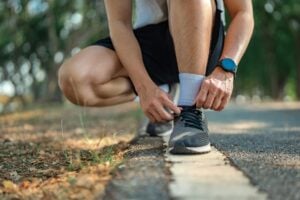 A close up of someone tying their running shoes while outside.
