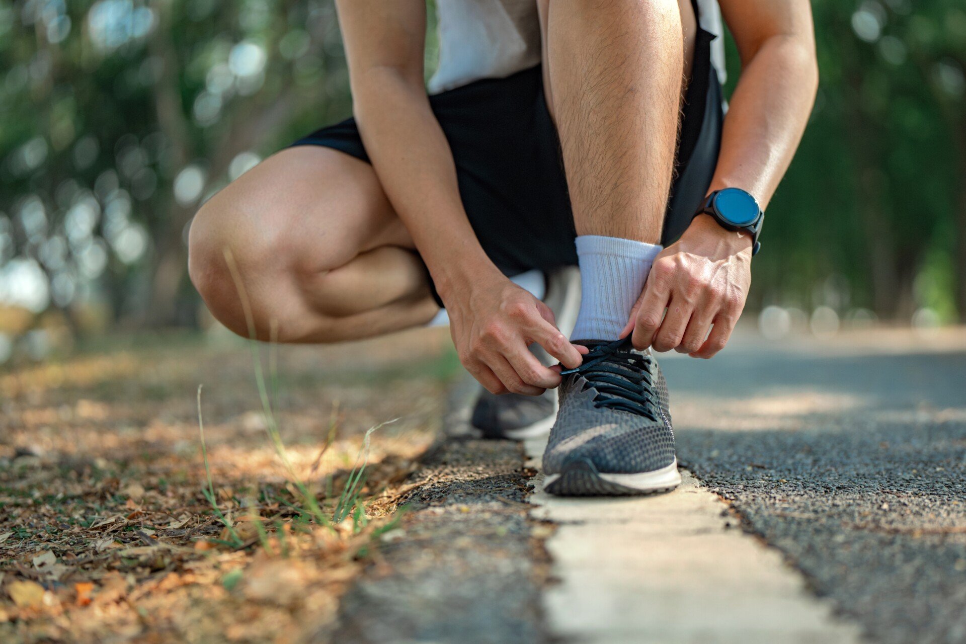 A close up of someone tying their running shoes while outside.