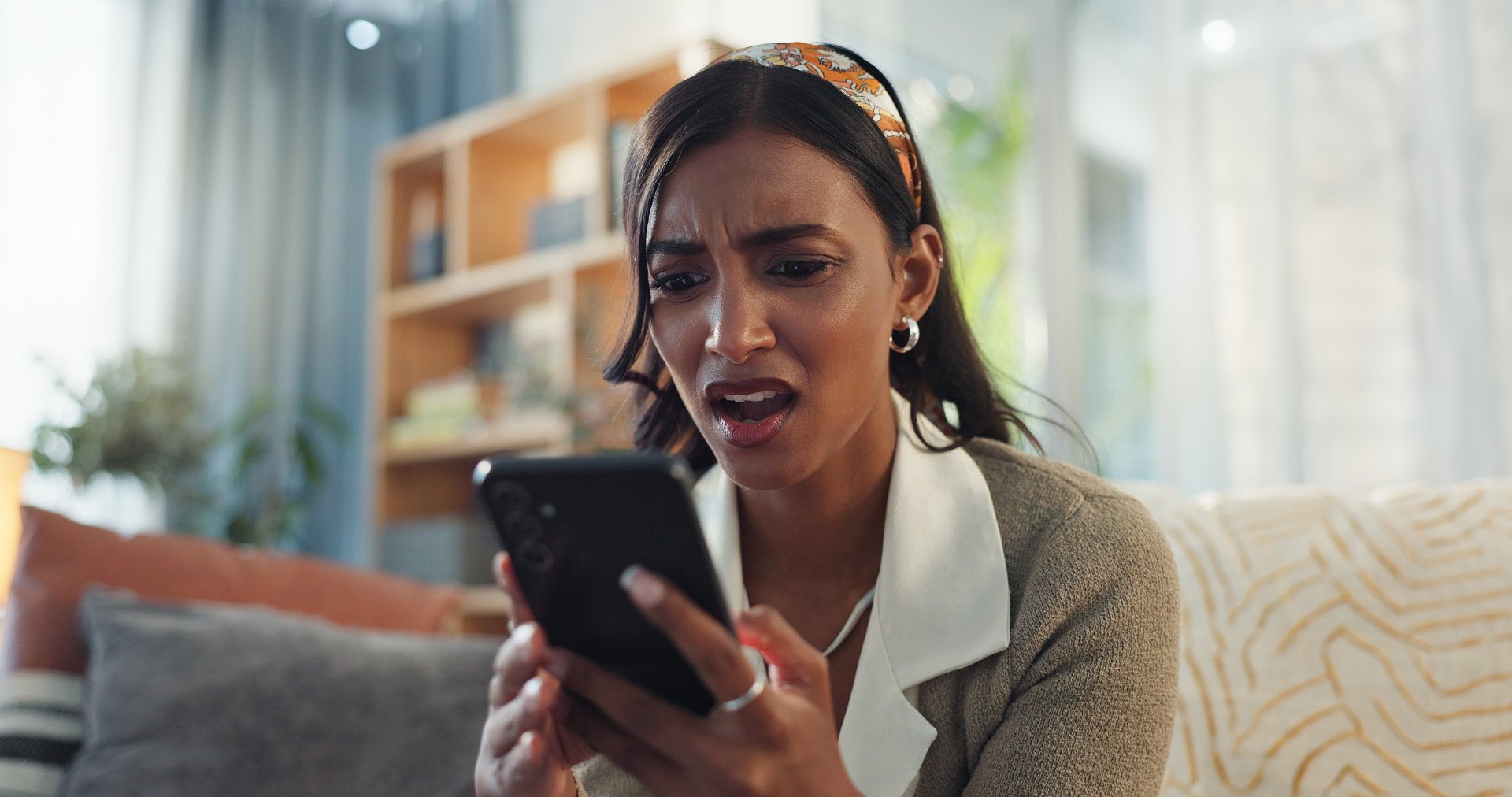 A woman looking shocked at her phone.