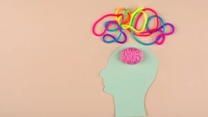 A cut out of a head with a model brain placed in it and colourful tangled rope above.