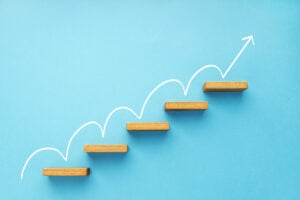 Rising arrow on staircase on blue background.