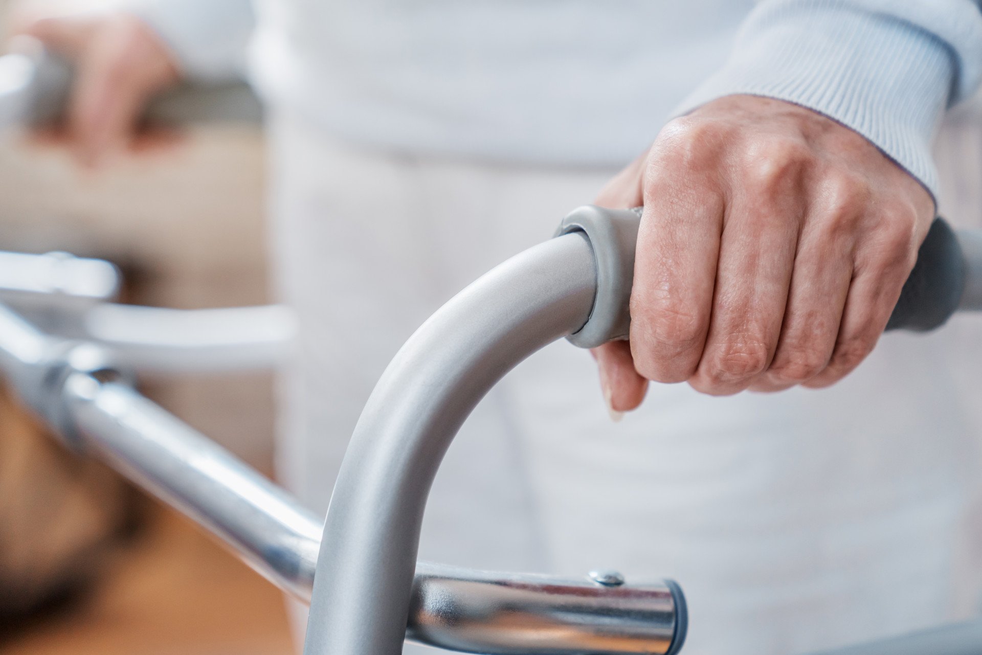 Close up of an older person's hands holding a walking frame.